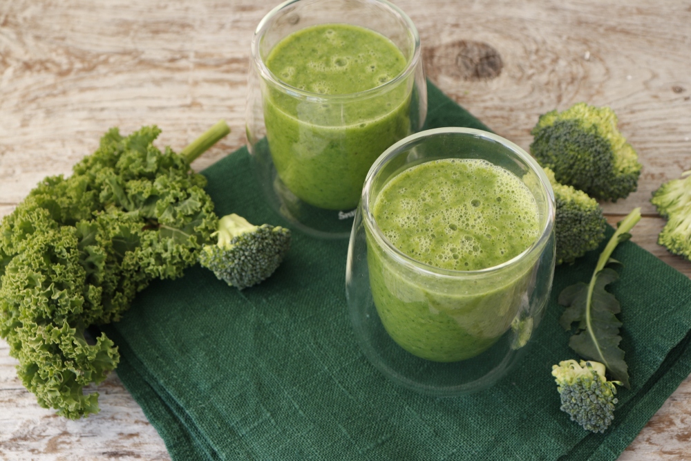 Broccoli and kale next to a fresh green juiced drink